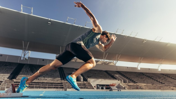 Runner using starting block to start his run on running track in a stadium. Athlete starting his sprint on an all-weather running track.