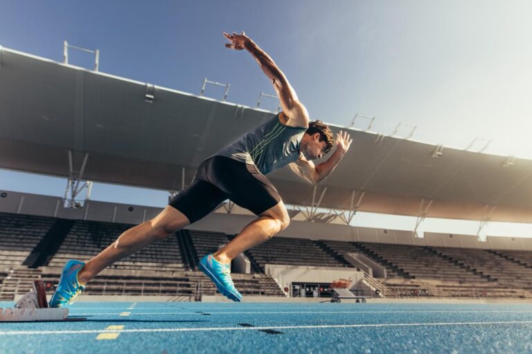 Runner using starting block to start his run on running track in a stadium. Athlete starting his sprint on an all-weather running track.