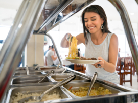 Woman serving food at a buffet restaurant and looking very happy - lifestyle concepts