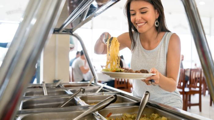 Woman serving food at a buffet restaurant and looking very happy - lifestyle concepts