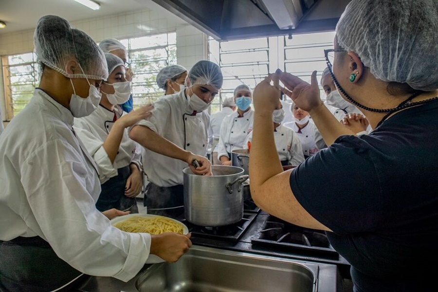 Imagem de um chef usando equipamentos de proteção individual (EPI) durante uma sessão prática de Treinamento Boas Práticas de Manipulação de Alimentos